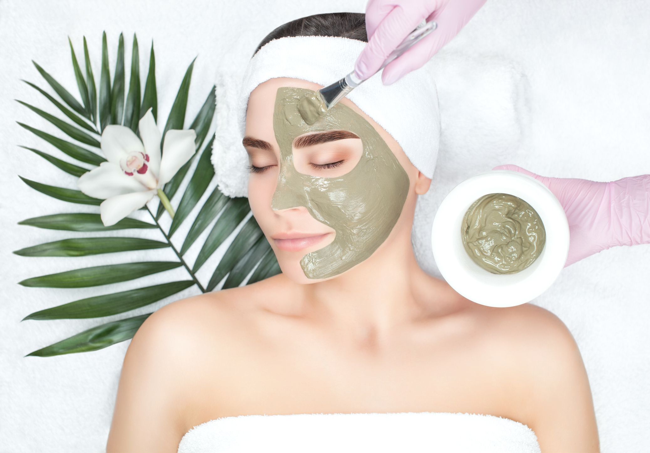 The procedure for applying a mask from clay to the face of a beautiful woman
